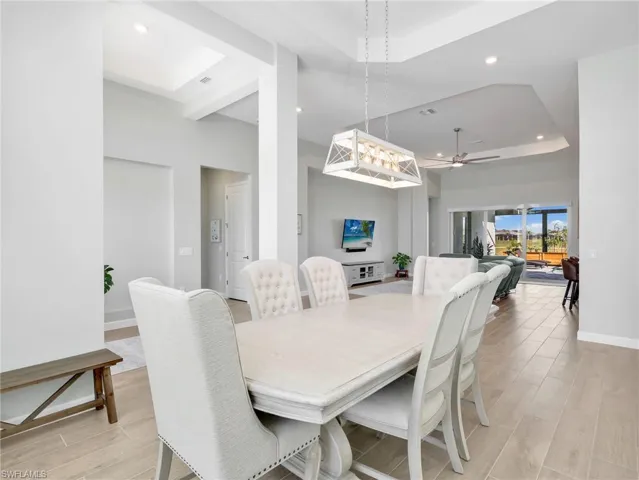 Dining area featuring a raised ceiling, recessed lighting, light wood-style flooring, and ceiling fan
