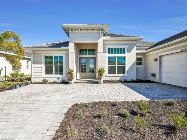 View of exterior entry featuring french doors, decorative driveway, a tiled roof, a garage, and stucco siding