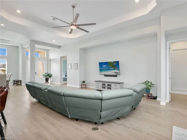 Living area with recessed lighting, wood tiled floors, ceiling fan, and a tray ceiling