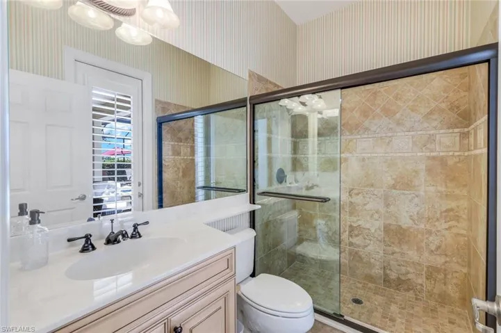 Bathroom with toilet, vanity, and an enclosed shower