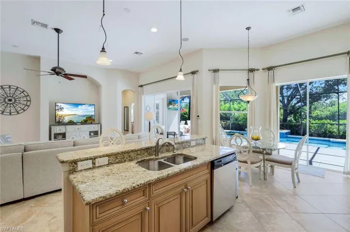 Kitchen with stainless steel dishwasher, sink, decorative light fixtures, and light tile patterned floors