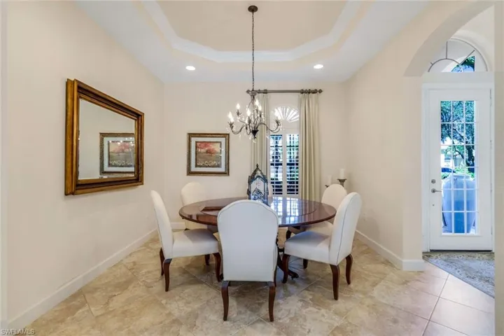 Dining area featuring light tile patterned flooring, a tray ceiling, and an inviting chandelier