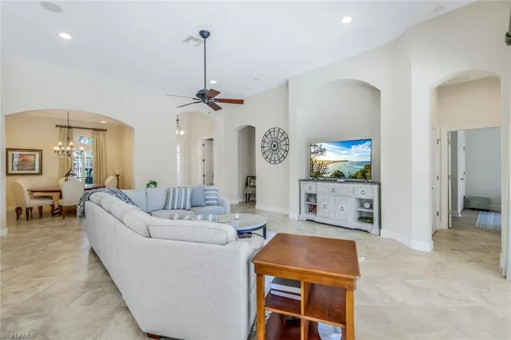 Tiled living room featuring ceiling fan with notable chandelier
