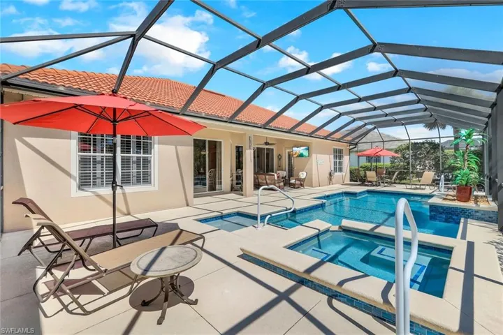 View of swimming pool with an in ground hot tub, a patio area, and a lanai