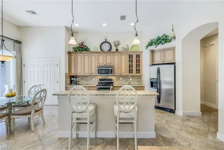 Kitchen with appliances with stainless steel finishes, a center island, light stone counters, and a kitchen breakfast bar
