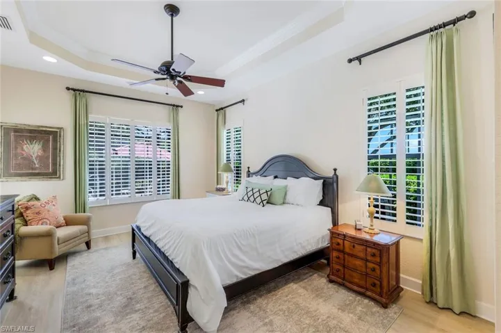 Bedroom featuring light hardwood / wood-style floors, multiple windows, and a tray ceiling