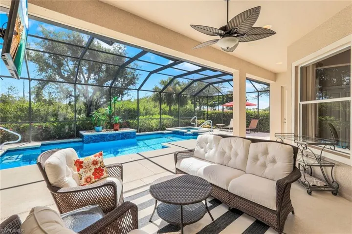View of pool featuring an outdoor living space, an in ground hot tub, a patio area, ceiling fan, and glass enclosure