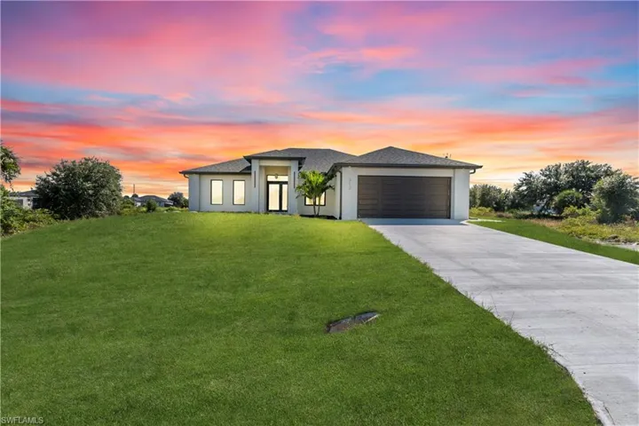 Prairie-style house with concrete driveway, a garage, a yard, stucco siding, and a shingled roof