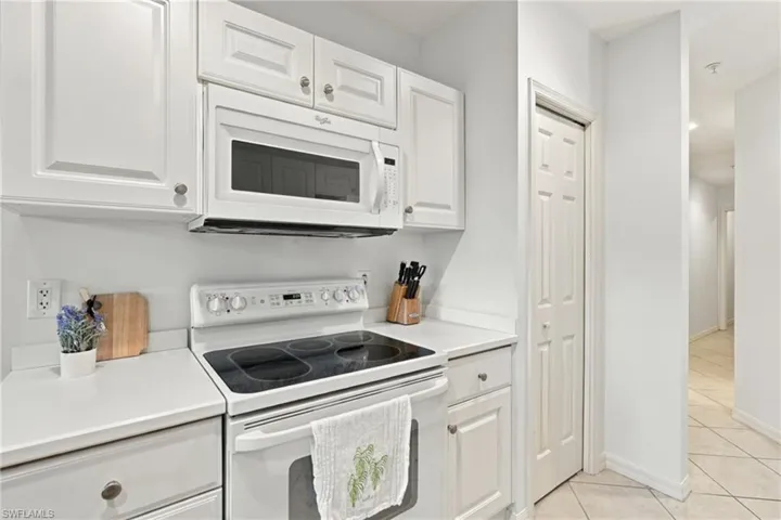 White shaker-style cabinetry, white countertop, white range, and a white over-the-range microwave