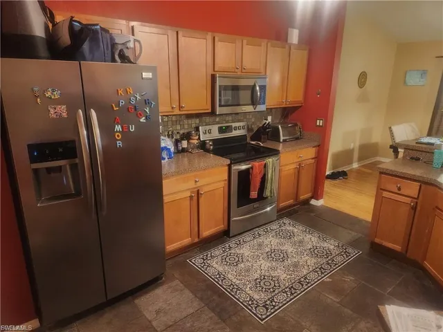 Kitchen featuring stainless steel appliances, decorative backsplash, and wood finish cabinetry