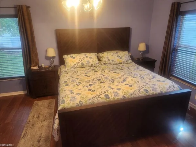 Bedroom featuring multiple windows and dark wood-style flooring
