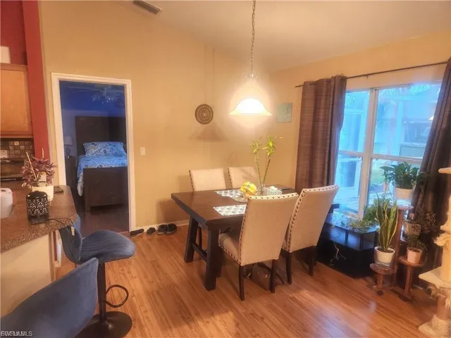 Dining space with vaulted ceiling and light wood-style flooring
