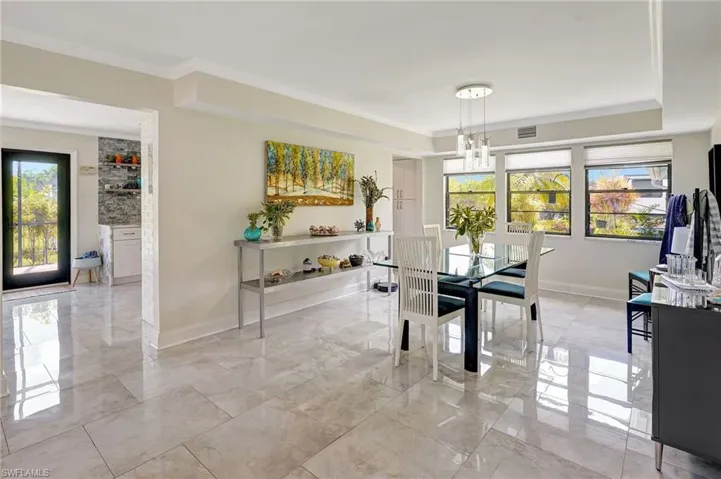 Dining area with marble finish floor and ornamental molding