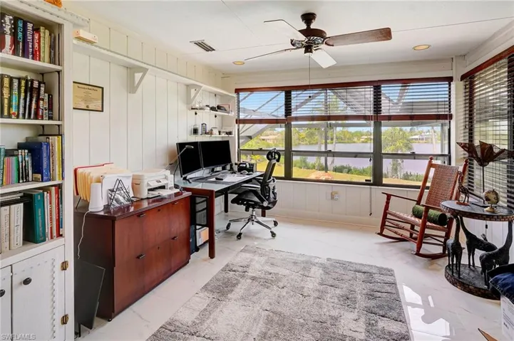Office area featuring a lake view, ceiling fan, a healthy amount of sunlight