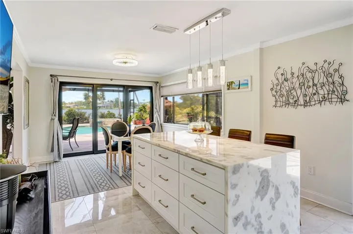 Kitchen with white cabinetry, light stone countertops, crown molding, and baseboards