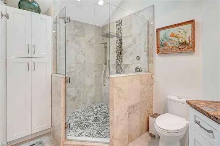 Bathroom with toilet, vanity, and a shower stall