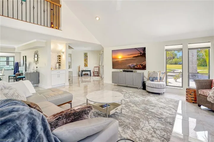 Living room with marble finish floor, a towering ceiling, and recessed lighting
