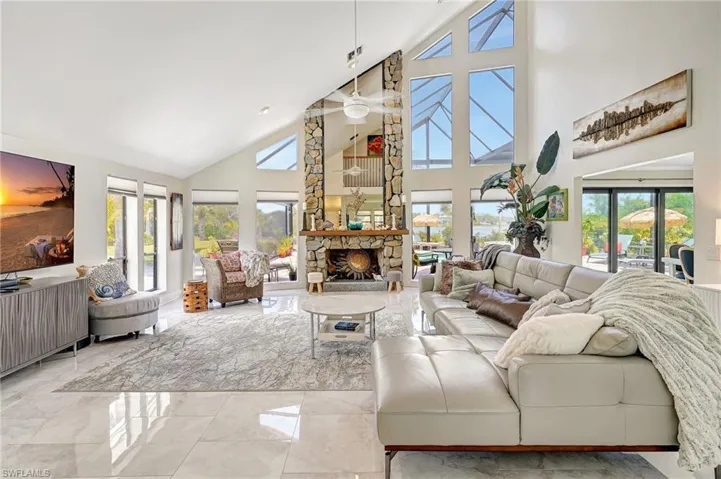 Living area featuring marble finish floor, a ceiling fan, high vaulted ceiling, and a fireplace