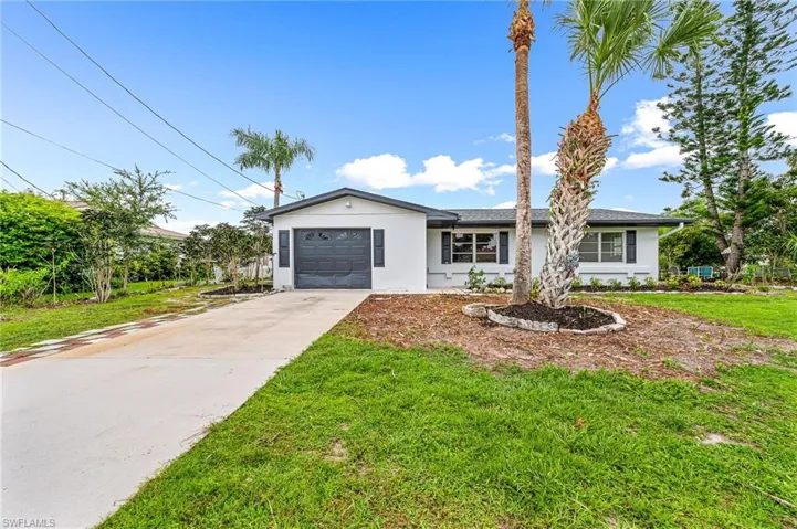 Single story home featuring a garage and a front yard