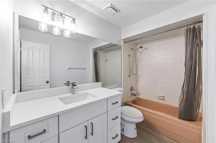 Full bathroom featuring hardwood / wood-style floors, vanity, toilet, and shower / bathtub combination with curtain