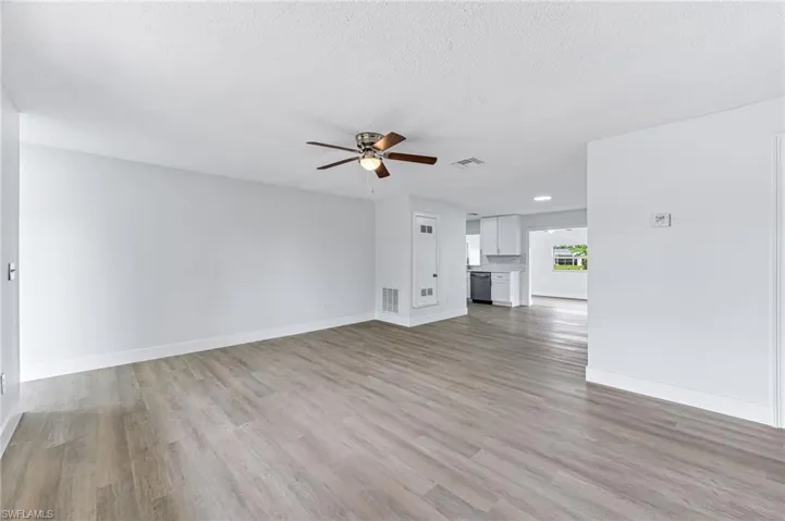 Unfurnished living room with hardwood / wood-style flooring, a textured ceiling, and ceiling fan