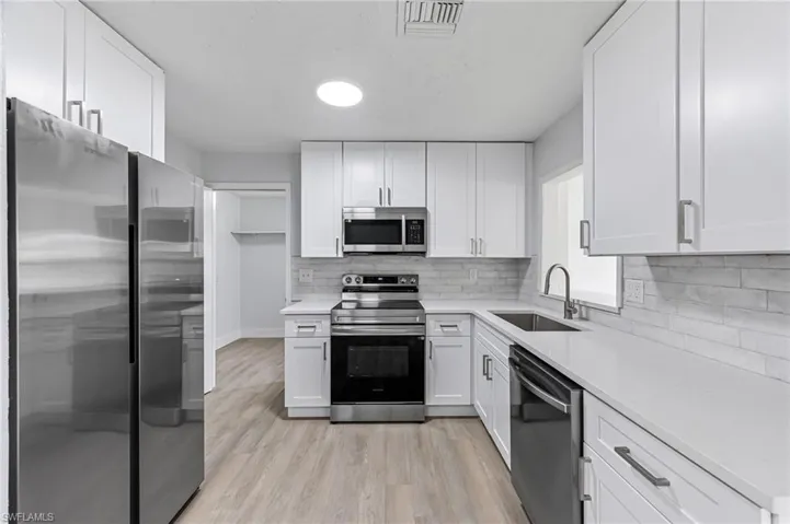 Kitchen featuring white cabinetry, stainless steel appliances, and light hardwood / wood-style flooring