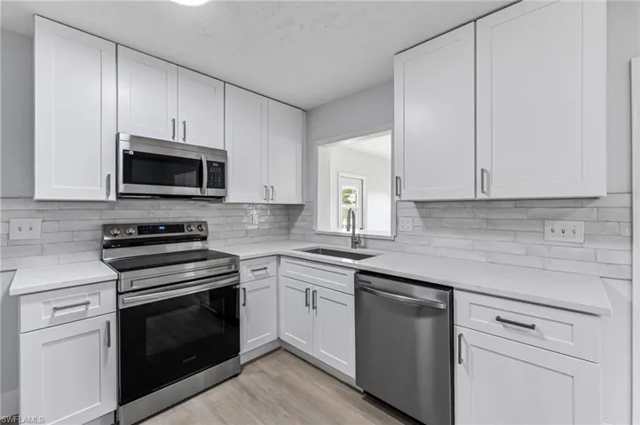 Kitchen featuring appliances with stainless steel finishes, light hardwood / wood-style floors, and white cabinetry