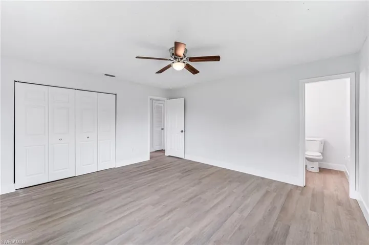 Unfurnished bedroom featuring light hardwood / wood-style floors, a closet, ensuite bath, and ceiling fan