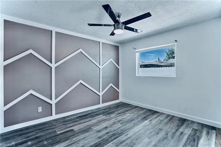 Unfurnished room featuring a textured ceiling, wood finished floors, and a ceiling fan