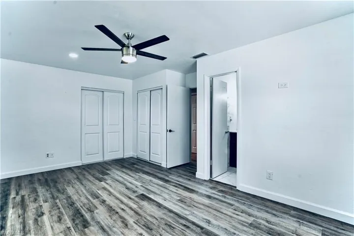Unfurnished bedroom with wood finished floors, ensuite bath, and a ceiling fan