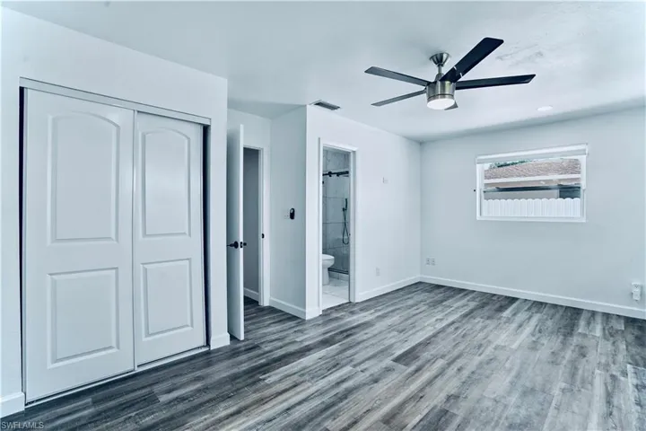 Unfurnished bedroom featuring a closet, dark wood finished floors, ensuite bathroom, and a ceiling fan