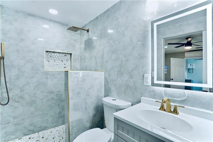 Bathroom with tile walls, a walk in shower, and vanity