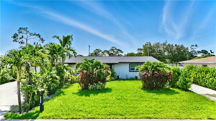 View of front of property featuring a front yard, stucco siding, and driveway