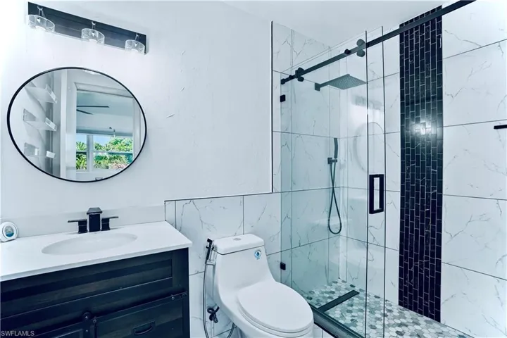 Full bath featuring tile walls, vanity, and a shower stall