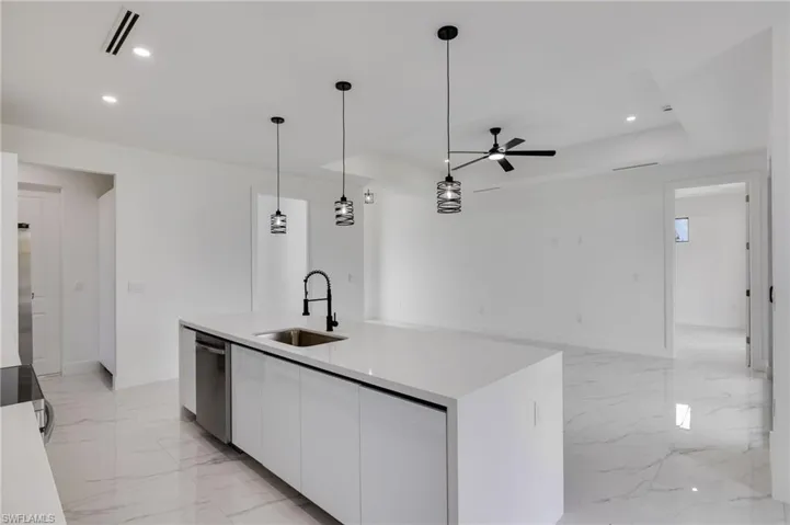 Kitchen featuring a center island with sink, white cabinets, pendant lighting, a tray ceiling, and stainless steel appliances