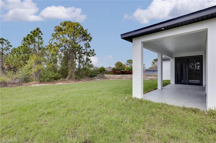 View of grassy yard featuring a patio area
