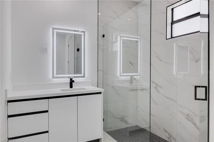 Full bathroom featuring vanity and a marble finish shower