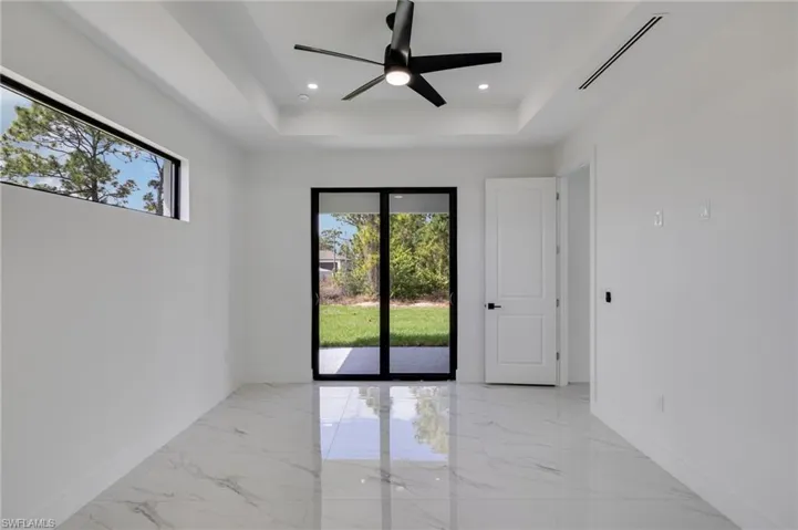 Spare room featuring a tray ceiling, a ceiling fan, recessed lighting, and light marble finish floors