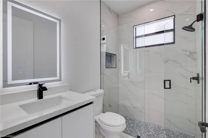 Bathroom with vanity and a marble finish shower