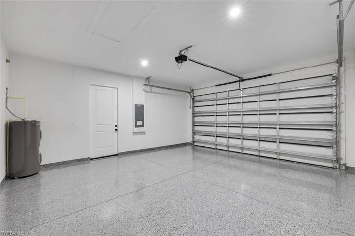 Garage with water heater, electric panel, and recessed lighting