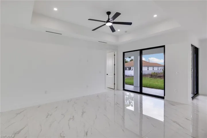 Spare room featuring a raised ceiling, ceiling fan, light marble finish floors, and recessed lighting