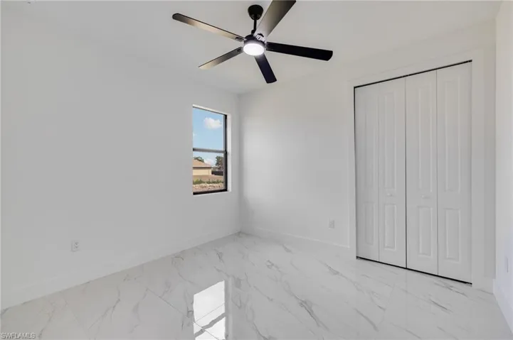 Unfurnished bedroom featuring ceiling fan, light marble finish floors, and a closet
