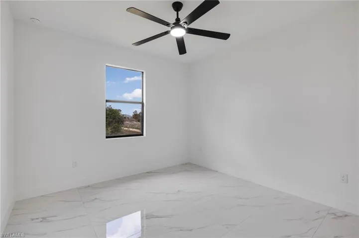 Unfurnished room featuring light marble finish flooring and ceiling fan