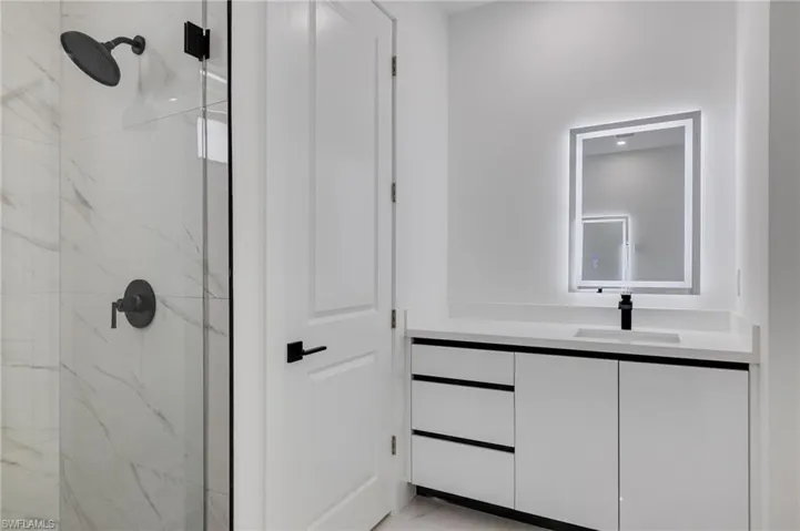 Bathroom with vanity and a marble finish shower