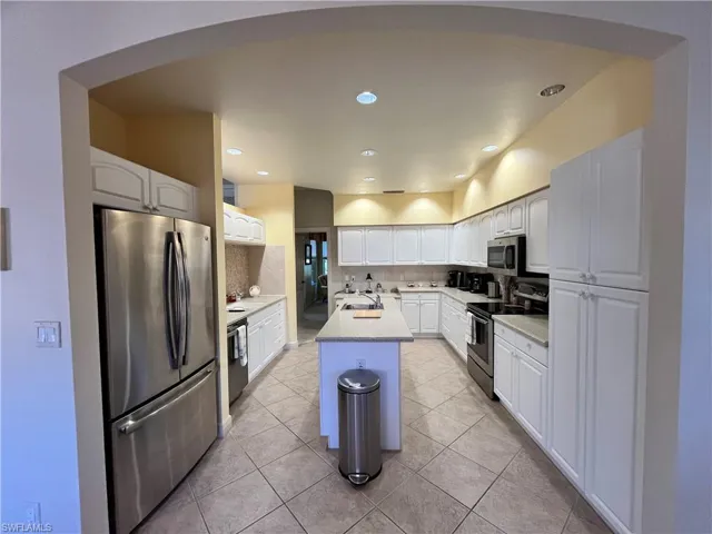Kitchen featuring sink, stainless steel appliances, a kitchen island, backsplash, and white cabinets