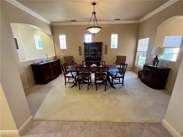 Dining room featuring ornamental molding, light carpet, and a wealth of natural light