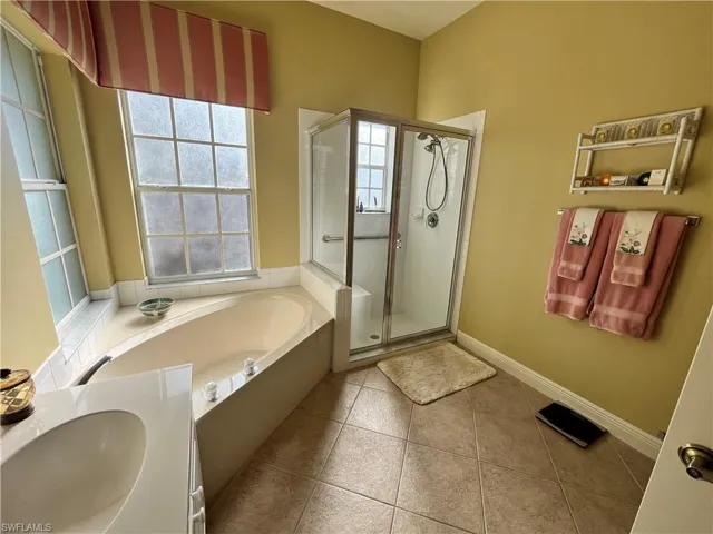 Bathroom featuring tile patterned flooring, separate shower and tub, and sink