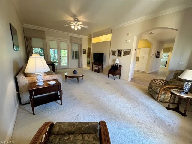 Living room with ceiling fan, crown molding, and light carpet