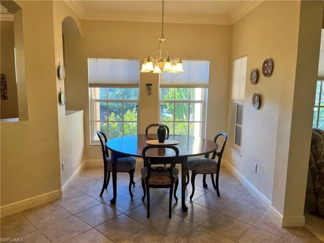 Dining area with an inviting chandelier, tile patterned floors, and ornamental molding