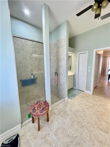 Bathroom featuring ceiling fan, tile patterned flooring, vanity, and tiled shower